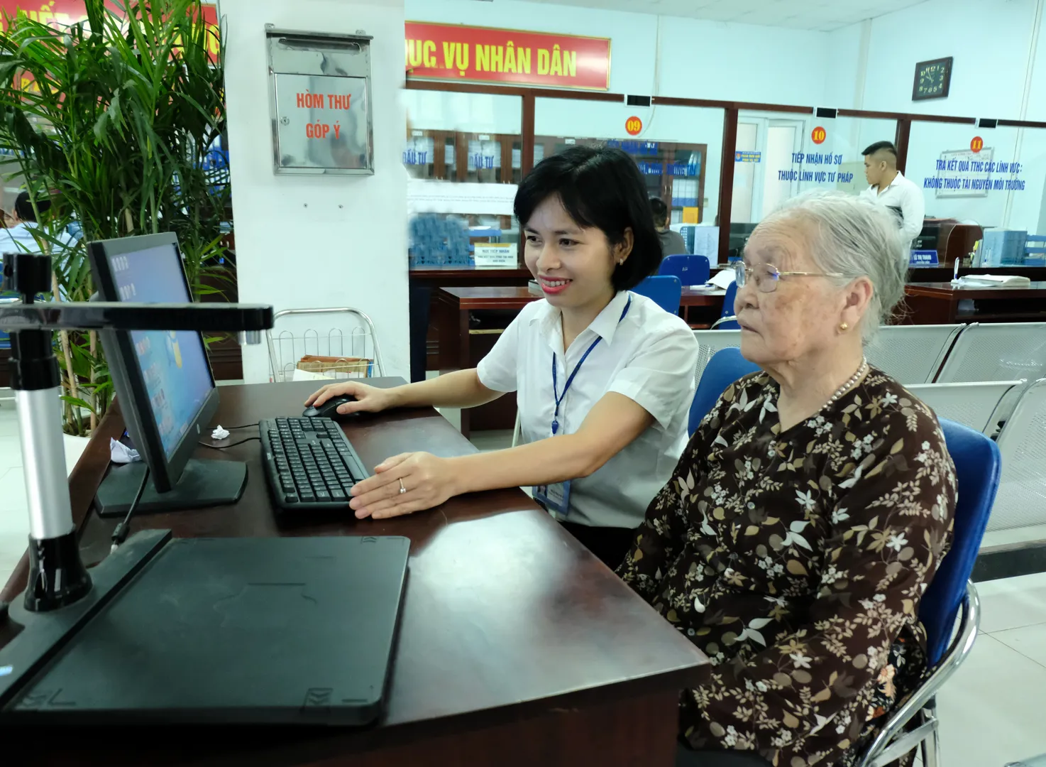 Cán bộ UBND quận Bắc Từ Liêm hướng dẫn người già làm thủ tục hành chính. Ảnh: Công Hùng