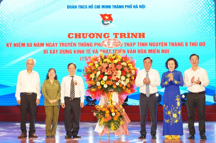 Phó Bí thư Thành ủy Hà Nội Nguyễn Văn Phong tặng hoa chúc mừng cựu Thanh niên xung phong tình nguyện Tháng 8 Thủ đô. Ảnh: Thủy Tiên
